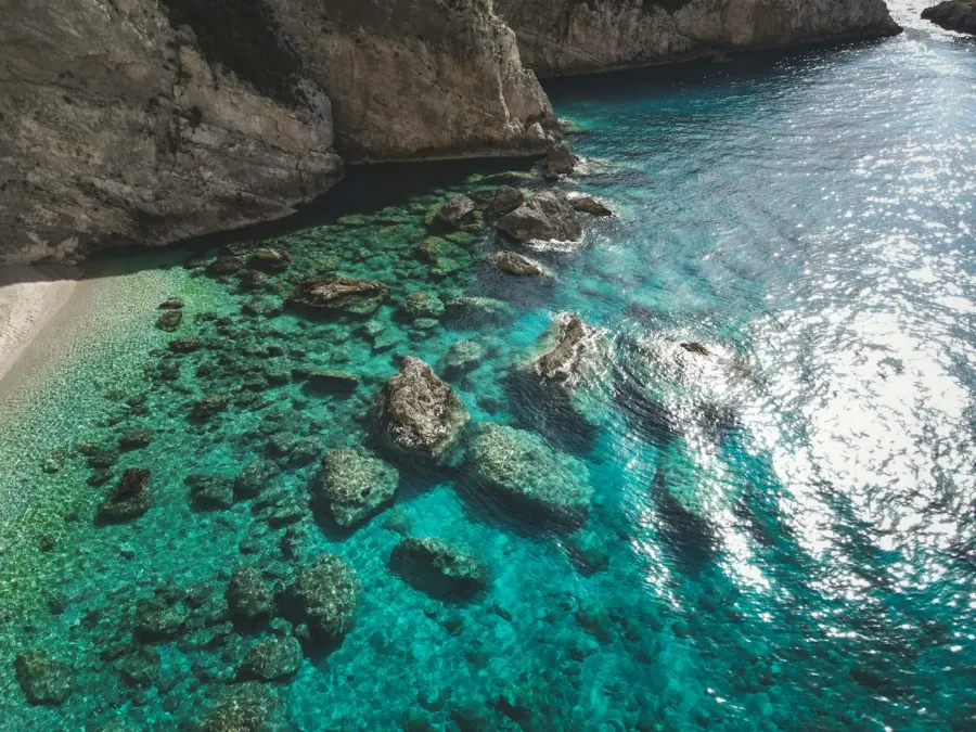 Eau turquoise cristalline et rochers au bord d'une plage méditerranéenne