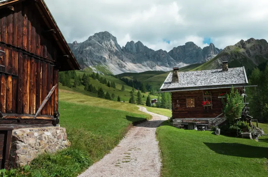 Chalets traditionnels dans un alpage des Dolomites entouré de prairies alpines verdoyantes